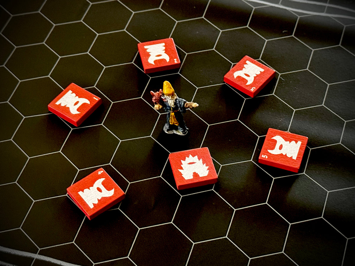Hex mat with a miniature figure of a wizard surrounded by red QuoDrox tiles.