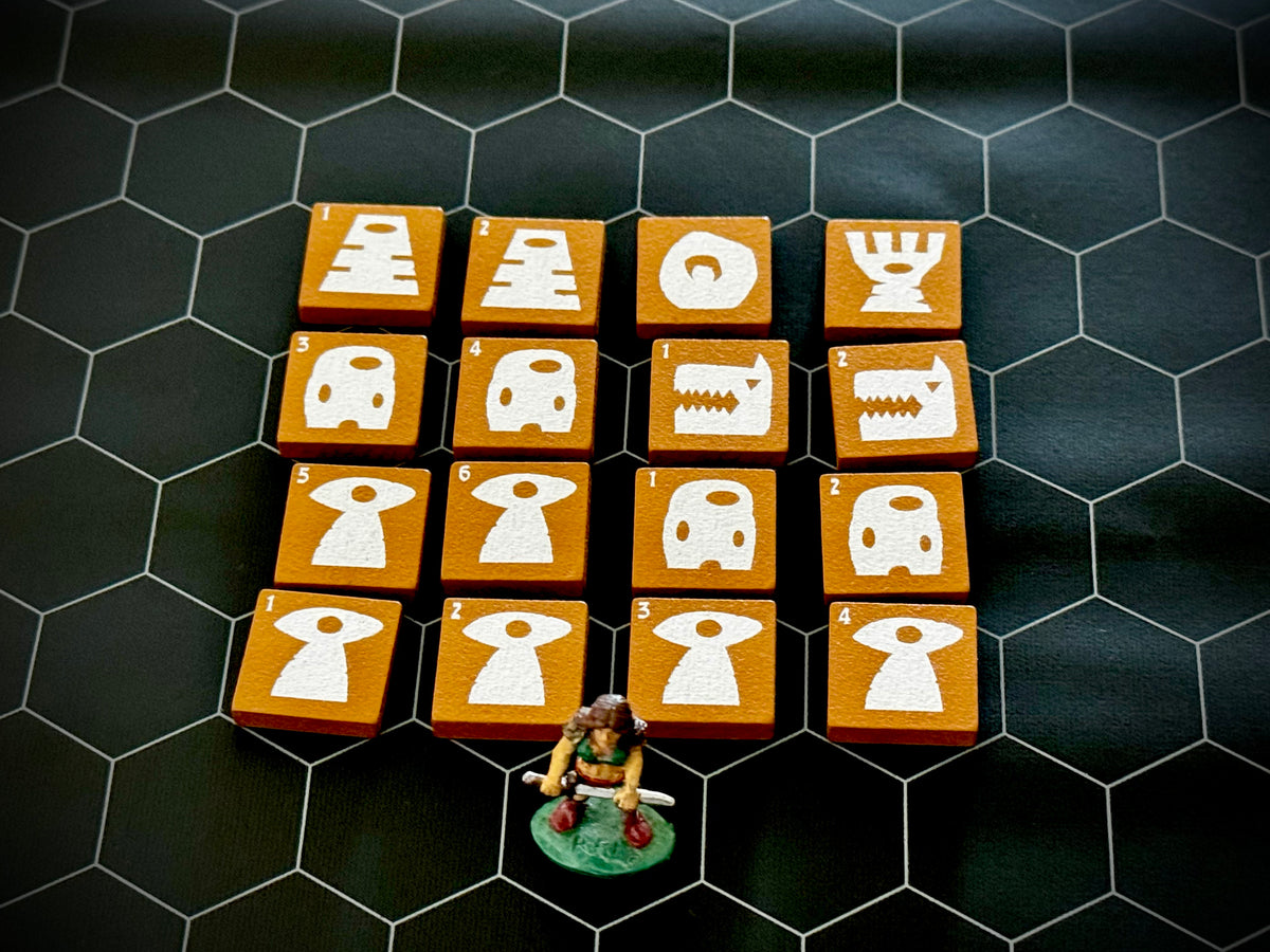 Yellow QuoDrox tiles showing the front designs on a black hex map.  A miniature figure stands in the front. 