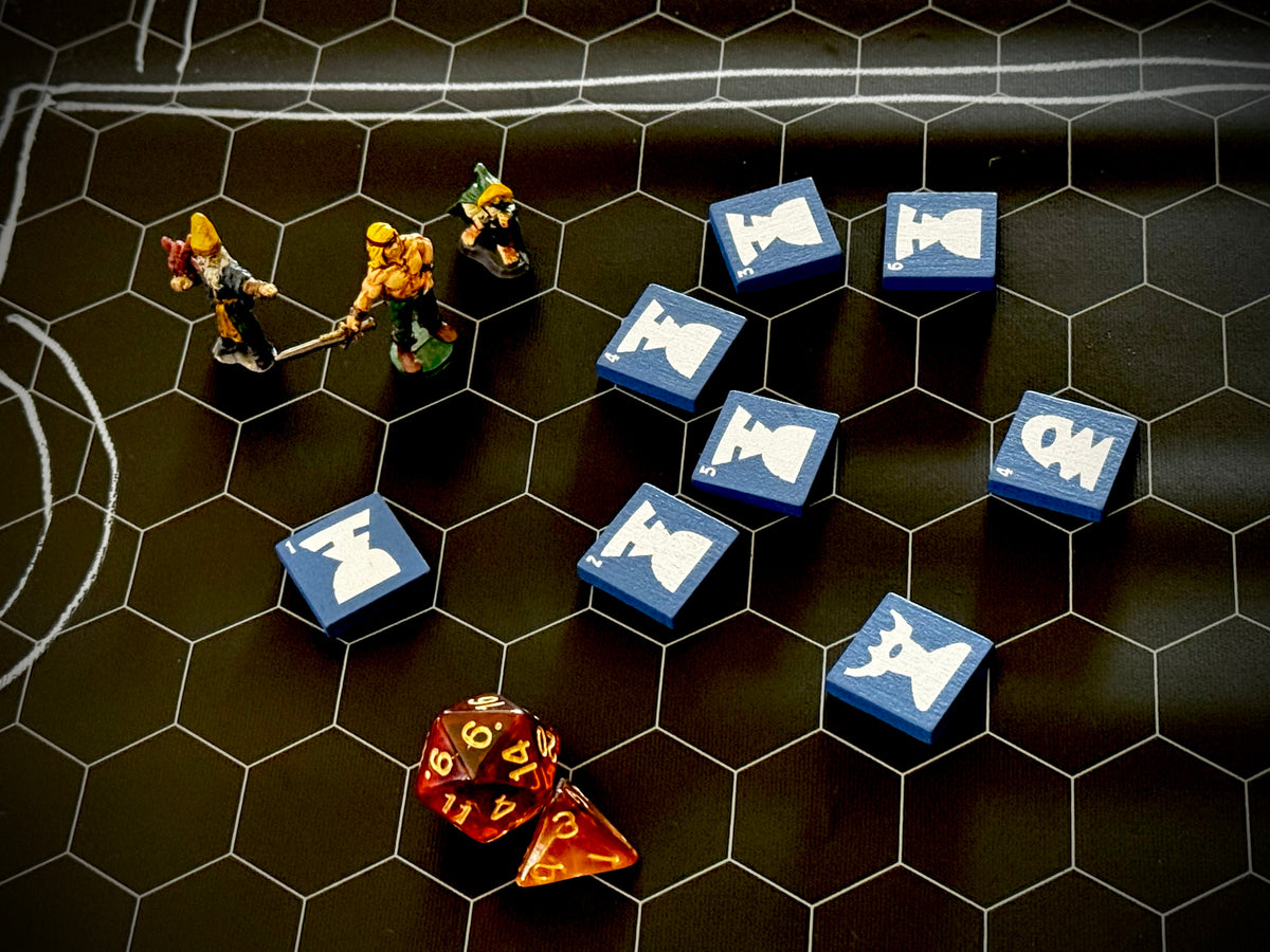 Hex mat with three miniature figure, dice, and several  blue QuoDrox tiles. 